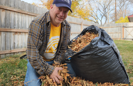 man in United Way shirt putting leaves into a bag