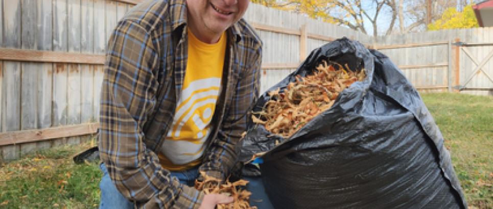 man in United Way shirt putting leaves into a bag